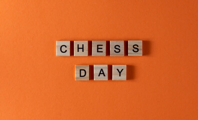 Chess day word phrase in wooden letters. Motivation and slogan. Orange background.