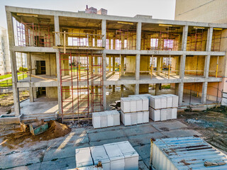 Construction of a monolithic reinforced concrete house. Close-up of a building under construction. The sun's rays illuminate the construction site. Shooting from a drone. Modern building in the city.