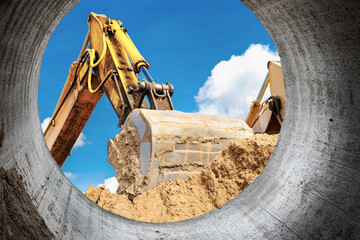 Powerful excavator at the construction site. View of the excavator through the pipe. Close-up of...