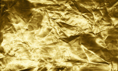 Gold foil background with light reflections. Golden textured wall.