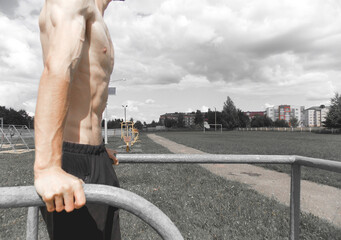 Push-ups on the uneven bars. A muscular guy trains on the uneven bars