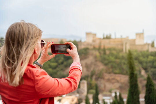 Lifestyle portrait of young woman having vacation in Europe taking picture to Alhambra in Granada