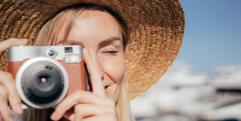 Close-up portrait of a woman taking a photo on a camera on a sunny summer day.