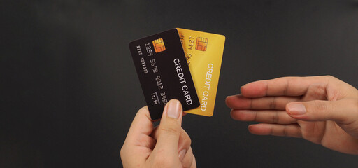 Hand is choosing two Credit Card in black and gold color on black background