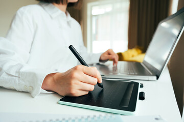 Faceless image of young woman graphic designer or digital artist using laptop computer and graphic...