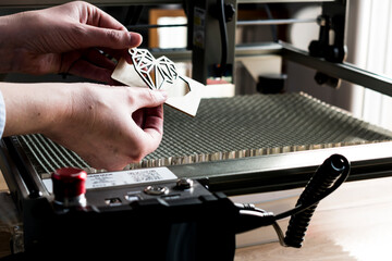 Laser engraving and cutting, woman holding an example of a cut out wooden heart