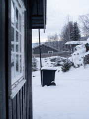 White vintage window in a black wooden house in a snow-covered landscape in Norway