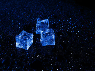 Ice cubes with water drops scattered on a black background in blue light