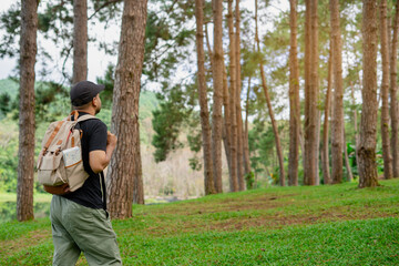 Naklejka premium Young happy man standing and looking at distance enjoying the fresh air in the forest. Male hiker with backpack and map with open arms enjoying and relax the nature.