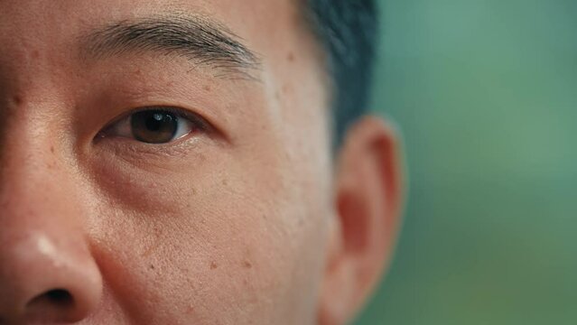Close-up macro shooting of male asian dark eyes korean chinese japanese ethnic man healthy 40s patient. Wrinkly face mature senior businessman client looking at camera ophthalmology medicine concept