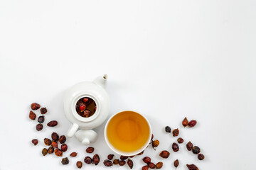 a glass cup of rosehip herbal tea on a white background, top view, along with green rosehip leaves, red flowers and dried fruits. Medicinal plants, herbal composition to increase immunity and vitamins