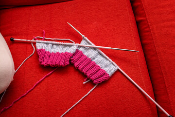 Knitting needles with colored wool on red velvet fabric. Concept made with hands.