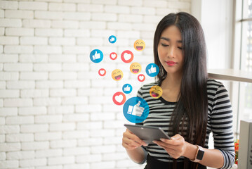Asian woman enjoy using tablet addiction to technology trends following and chatting with icons on social networks. in the morinig with coffee. Social medias and technology concept.