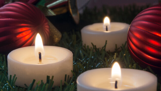 image with three lighted candles and christmas ornaments