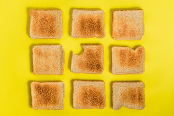Top view of a pattern of various slices of toasted bread arranged on a yellow background. A bitten slice. Breakfast concept. Appetite concept
