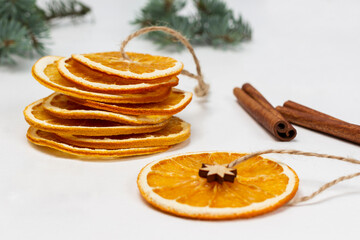 Dry orange slices on a string, cinnamon sticks and sprigs of spruce.