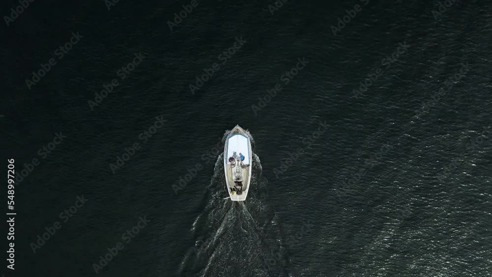 Sticker Aerial footage above a white boat sailing in peaceful deep blue water in Sweden in daylight