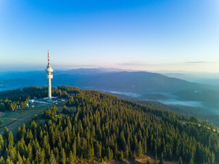 Obraz premium Tower Snezhanka in Rhodope mountains with fog, forest, sunbeams and sunny clouds