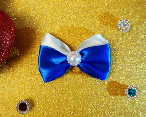 a blue and white bow for dogs with long hair lies on a golden shiny background . view from above. ...