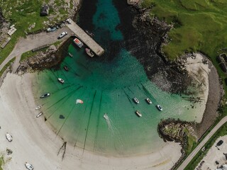 Top view of a beach and a turquoise lagoon of Tiree in Scotland, with boats and a kite surfer