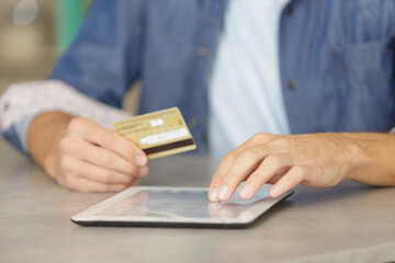 hands holding credit card and using tablet
