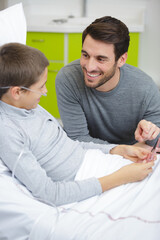 Obraz premium boy in bed at the hospital with his father