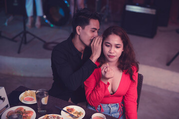 The young woman is not happy to hear the sex joke that the man whispered to her about her revealing clothes. An awkward situation for the woman on their first date.