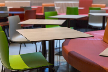 Multicolored empty tables at the food court in the mall. Entertainment and recreation. Close-up.