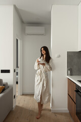 beautiful woman stand with a cup of tea in hands in the kitchen. apartment after renovation