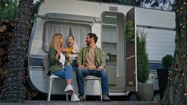 Caucasian family father mother and child girl kid daughter talking speaking conversation discus dream talk dreaming speak funny communication fun in camping campsite sitting near van trailer in trip
