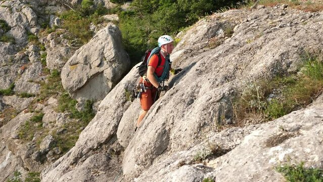 Young male climber climbs a mountain on a difficult route