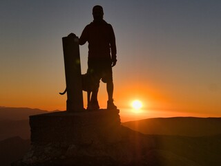 Silhouette of a man on the peak of a mountain and admiring the sunrise scene