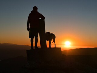 Silhouette of a man on the peak of a mountain and admiring the sunrise scene