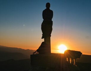 Silhouette of a man on the peak of a mountain and admiring the sunrise scene