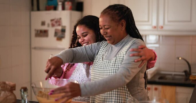 Mother and daughter preparing fruit cake at home - Family and cooking concept
