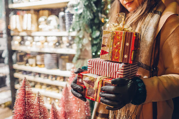 Close up of Christmas gift boxes in female hands. Woman holding presents after New year shopping - obrazy, fototapety, plakaty