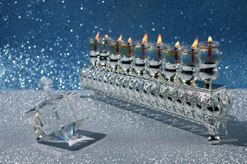 Jewish holiday Hanukkah background with oil menorah and dreidel with letters Gimel and Nun.