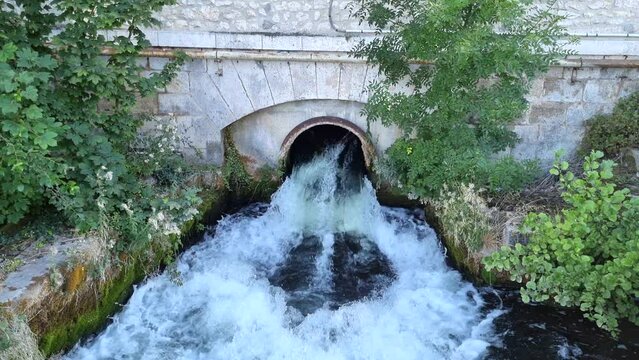 Water falling from medieval bridge in French town. High quality 4k footage