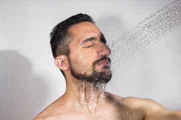 Water pours on the guy's face on a white background. The concept of taking a shower and washing your head.