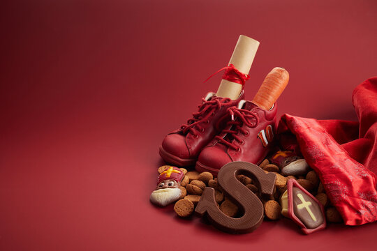 Saint Nicholas - Sinterklaas day with shoe, carrot and traditional sweets on red background