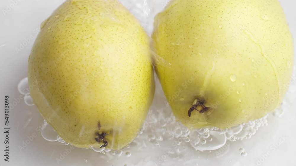 Poster yellow pear on a blue dark background with drops of water rolling down the pear and flowing splashin