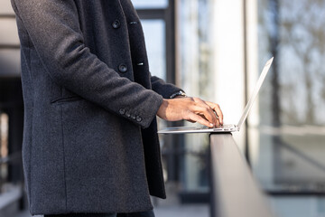 Close up of business man hands using modern technology, mobile phone and laptop outdoors