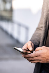 Close up of business man hands using modern technology, mobile phone and laptop outdoors