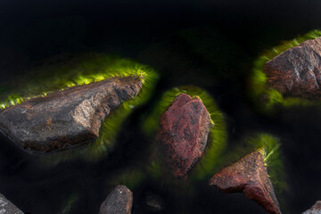 Felsen im Wasser mit abstrakten Algen. Felsen mit unwirklichem grünem Rand. Fremd wirkende Formation.
Rocks in the water with abstract seaweed. Rocks with unreal green edge. Alien formation.
 - obrazy, fototapety, plakaty