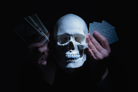 Conceptual image: gambling addiction. Money, cards and skull as symbol of loss of time, opportunities, future and living life