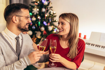 Couple drinking wine and laughing while sitting around a dining table during a dinner party