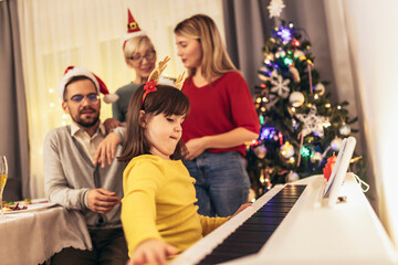 Family while enjoying music that their daughter playing on piano during Christmastime
