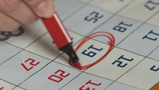person marks an important date on a wall calendar