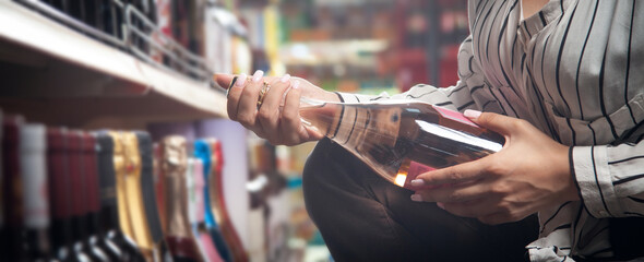 Woman buying champagne in supermarket.