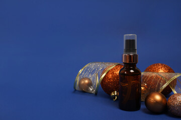 Cosmetic product oil or face serum on blue christmas background with golden decorations. Winter skin care